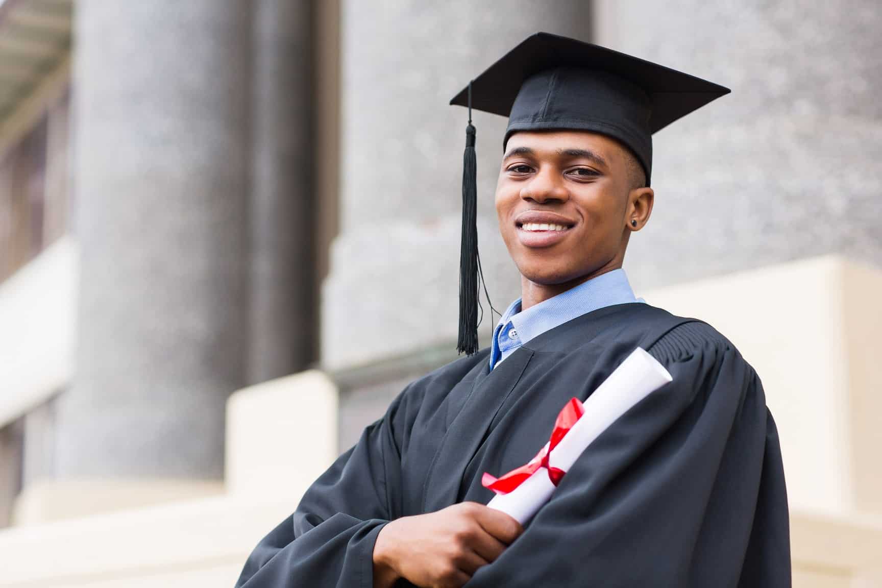 portrait of african american male graduate standing outside college